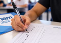 Estudante utiliza caneta esferográfica preta de material transparente para preencher o cartão de respostas do Enem 2026.