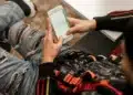 Jovem com mochila consulta o celular, como quem confere o cartão de confirmação do Enem 2026