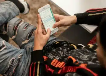 Jovem com mochila consulta o celular, como quem confere o cartão de confirmação do Enem 2026