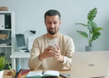 Homem sorri ao conferir a carteira de trabalho digital no celular depois de ser contratado