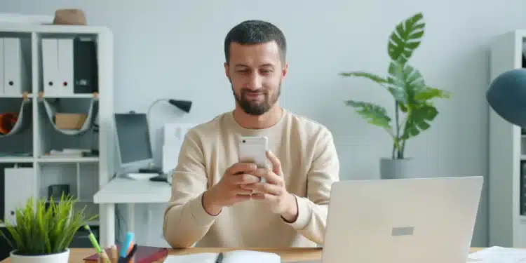 Homem sorri ao conferir a carteira de trabalho digital no celular depois de ser contratado