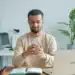 Homem sorri ao conferir a carteira de trabalho digital no celular depois de ser contratado