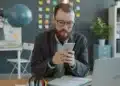 Servidor de óculos usa o celular na mesa do escritório para indicar órgão no SouGov, etapa do CNU 2 para ATDS e ATJD
