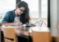 Candidata do concurso TRT-4 estudando com livro e caneta em uma mesa