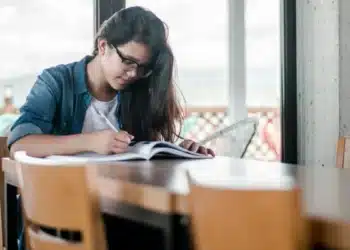 Candidata do concurso TRT-4 estudando com livro e caneta em uma mesa