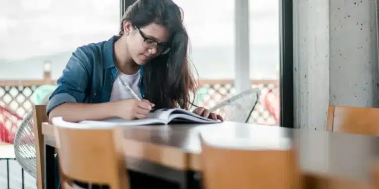 Candidata do concurso TRT-4 estudando com livro e caneta em uma mesa