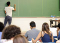 Imagem ilustrativa sobre cursinhos populares mostra professor que escreve conteúdo de biologia no quadro verde diante de estudantes em sala de aula