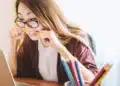 Mulher estuda em frente ao computador com lápis na mão, cena que ilustra o curso de Português online de 80 horas