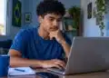 Jovem acessa notebook, representando a consulta de vagas e a inscrição em cursos gratuitos de idiomas do Mover.