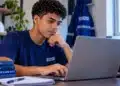Jovem acessa notebook, representando a inscrição em cursos gratuitos de qualificação profissional oferecidos pelo Senai e pela Transpetro.