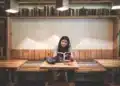 Mulher lê um livro em biblioteca, imagem para o Dia Nacional da Língua Portuguesa, celebrado em 5 de novembro