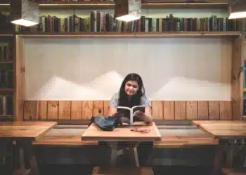 Mulher lê um livro em biblioteca, imagem para o Dia Nacional da Língua Portuguesa, celebrado em 5 de novembro