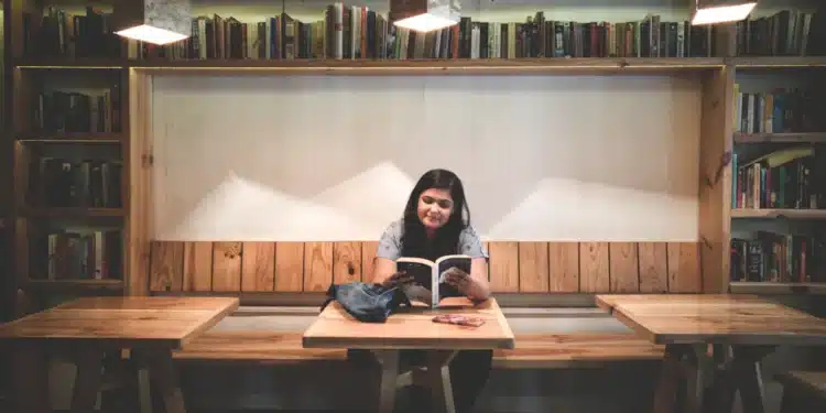Mulher lê um livro em biblioteca, imagem para o Dia Nacional da Língua Portuguesa, celebrado em 5 de novembro