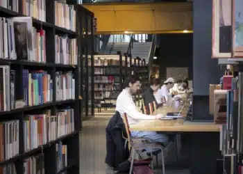 Estudantes leem e estudam em mesas de uma biblioteca moderna, cena ligada ao Dia Nacional do Livro
