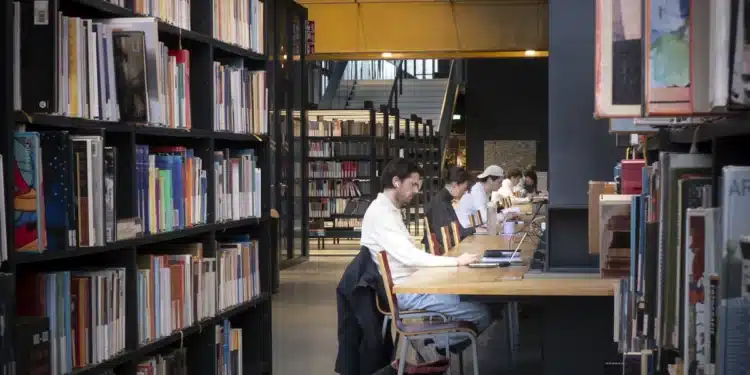 Estudantes leem e estudam em mesas de uma biblioteca moderna, cena ligada ao Dia Nacional do Livro