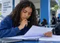 Estudante analisa documentos em uma universidade, representando os direitos previstos na Lei do Estágio sobre bolsa, jornada e recesso.