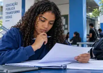Estudante analisa documentos em uma universidade, representando os direitos previstos na Lei do Estágio sobre bolsa, jornada e recesso.