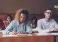 Estudantes concentrados escrevendo em sala, imagem sobre como dividir o tempo no Enem 2026