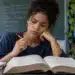 Estudante consulta um dicionário aberto durante os estudos, representando a dúvida de português sobre o uso correto das palavras “contumaz” e “costumaz”.