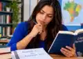 Estudante com livro de Língua Portuguesa analisa a dúvida gramatical entre “favorecer o” e “favorecer ao”.