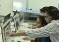 Professor orienta alunos no computador em sala de aula, exemplo de educação digital prevista na LDB