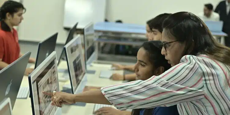 Professor orienta alunos no computador em sala de aula, exemplo de educação digital prevista na LDB