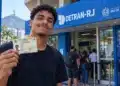 Jovem apresenta carteira de identidade em frente a uma unidade do Detran-RJ, ilustrando o atendimento sem agendamento destinado aos estudantes que vão fazer o Enem.