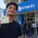 Jovem apresenta carteira de identidade em frente a uma unidade do Detran-RJ, ilustrando o atendimento sem agendamento destinado aos estudantes que vão fazer o Enem.