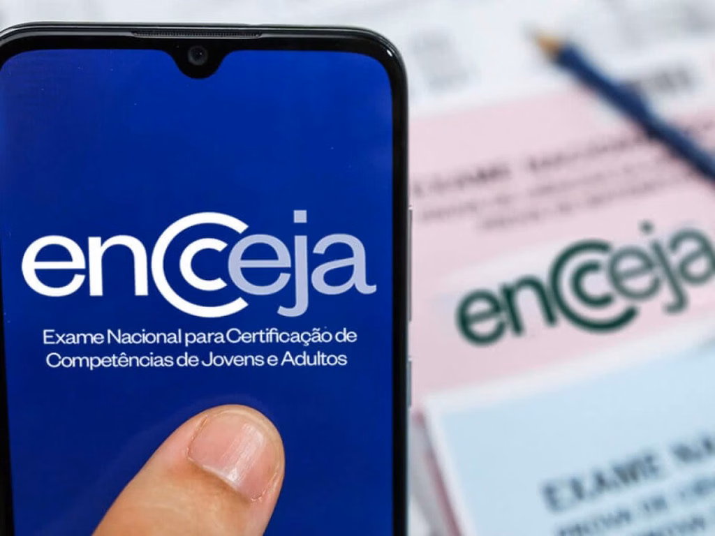 Celular com o logotipo do Encceja na tela, à frente de cadernos de prova do exame, em referência às opções de certificação para jovens nem-nem