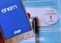 Celular com identificação do Enem em frente a caderno de prova do exame.