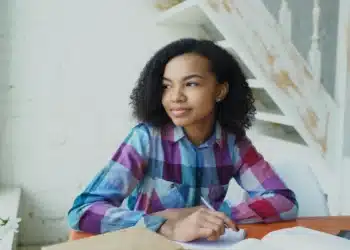 Jovem candidata do Enem 2026 estudando em uma mesa com cadernos e livros
