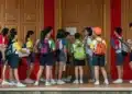 Estudantes com mochilas reunidos na entrada de uma escola, cena que lembra a chegada ao Enem 2026