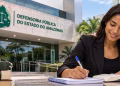 Estudante de Direito escrevendo em caderno, com livros jurídicos e representação da Justiça em imagem sobre estágio na Defensoria Pública do Amazonas.