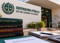 Imagem ilustrativa de livros de Constituição Federal, Código de Processo Civil, Direito Penal e Legislação Especial diante de um prédio com o nome da Defensoria Pública do Rio Grande do Norte, representando o estágio em Direito na Defensoria