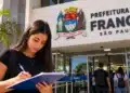 Jovem escreve em frente à Prefeitura de Franca, representando o estágio com inscrições abertas até 29 de outubro.