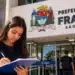 Jovem escreve em frente à Prefeitura de Franca, representando o estágio com inscrições abertas até 29 de outubro.