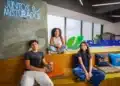 Três jovens em ambiente da Suzano, ao lado do logotipo da empresa e de um letreiro com a frase “Juntos e misturados”.
