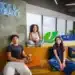 Três jovens em ambiente da Suzano, ao lado do logotipo da empresa e de um letreiro com a frase “Juntos e misturados”.