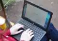 Estudante sentada em banco ao ar livre usa notebook para fazer a inscrição nas vagas remanescentes do Fies