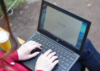 Estudante sentada em banco ao ar livre usa notebook para fazer a inscrição nas vagas remanescentes do Fies