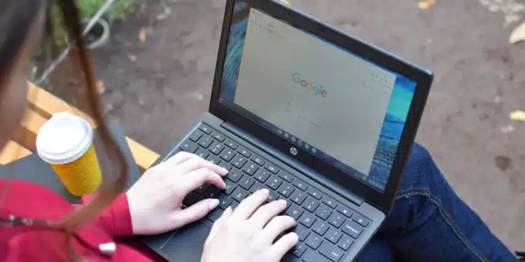 Estudante sentada em banco ao ar livre usa notebook para fazer a inscrição nas vagas remanescentes do Fies