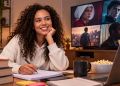 Imagem ilustrativa de estudante sorridente fazendo anotações em caderno, com livros, notebook e pipoca na mesa e uma televisão ao fundo exibindo cenas de filmes e séries, em referência ao repertório para a redação do Enem