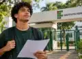 Estudante com mochila e documento nas mãos em frente a um Instituto Federal, representando os vestibulares de graduação gratuita para 2027.