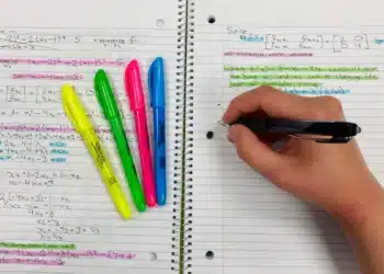 Pessoa escreve em caderno com canetas coloridas enquanto revisa as regras de hífen com prefixo