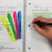 Pessoa escreve em caderno com canetas coloridas enquanto revisa as regras de hífen com prefixo