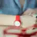 Estudante com relógio vermelho no pulso escreve durante prova, ilustrando os horários do Enem 2026