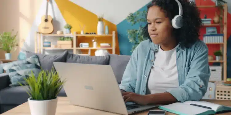 Jovem de fones de ouvido estuda no notebook em casa, rotina de quem faz curso de inglês básico online
