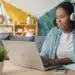 Jovem de fones de ouvido estuda no notebook em casa, rotina de quem faz curso de inglês básico online
