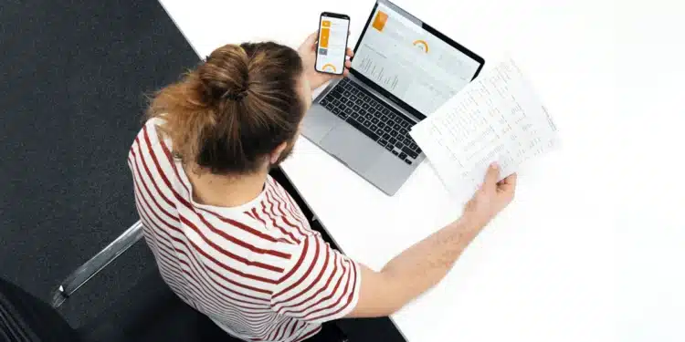 Mulher com notebook e papéis na mesa prepara pedido de isenção de taxa em concurso federal pela Lei 13.656