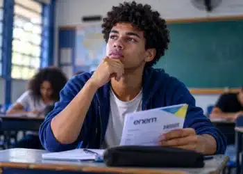 Estudante em sala de aula segura documento do Enem, representando a possibilidade de utilização da melhor nota entre as três últimas edições do exame no Sisu 2027.